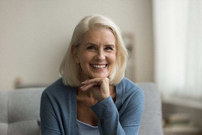 Senior woman sitting on grey chair smiling