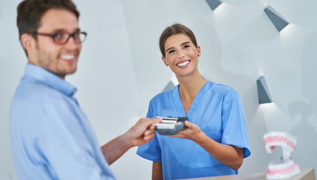 Patient smiling while paying for cost of cosmetic dentistry in Fort Worth