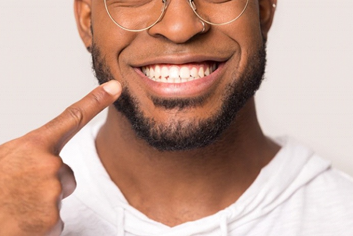 man with dental crowns in Fort Worth pointing to his smile