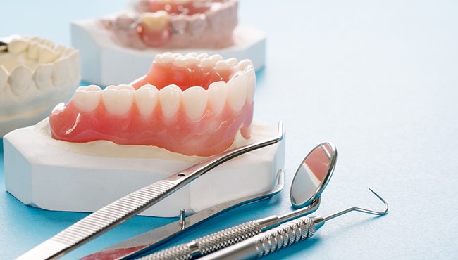 A close-up of a complete denture against a blue background