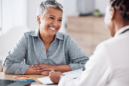 a woman smiling while speaking with her dentist