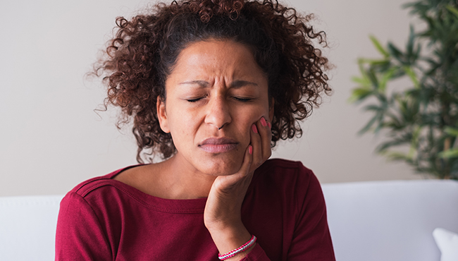 Woman in need of emergency dentistry holding cheek