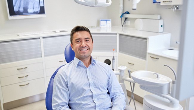 Man sitting in dental chair smiling visiting emergency dentist in Fort Worth, TX