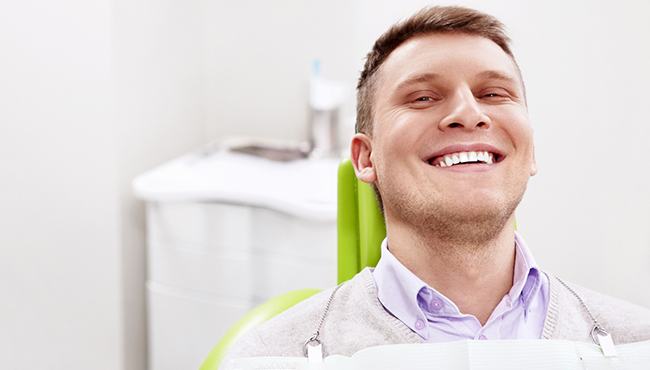 Male patient sitting back in dental chair and smiling