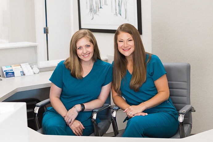 Two dental team members at dental office front desk