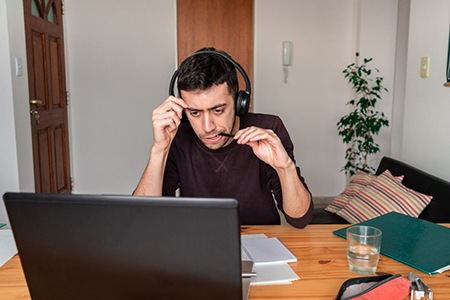 a person studying and chewing on the tip of a pen while sitting at a desk