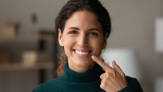 Woman at home pointing to her smile
