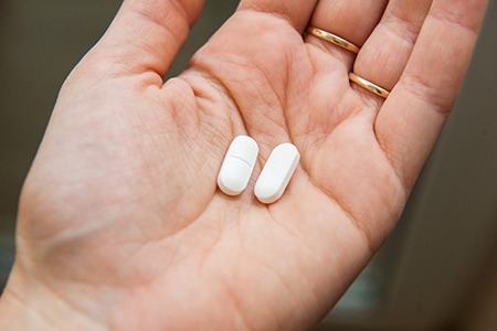Close-up of a hand holding two white painkillers