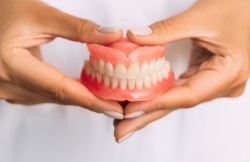 Hands holding full dentures