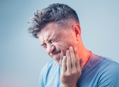 Man holding his cheek in pain