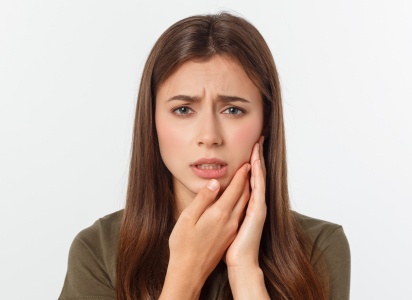 Young woman holding the side of her face in pain