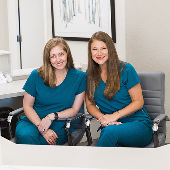 Two smiling Fort Worth dental team members sitting next to each other
