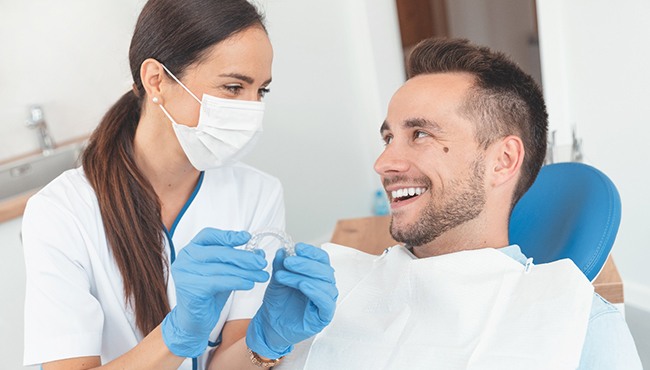 Dentist holding Invisalign tray and smiling at patient