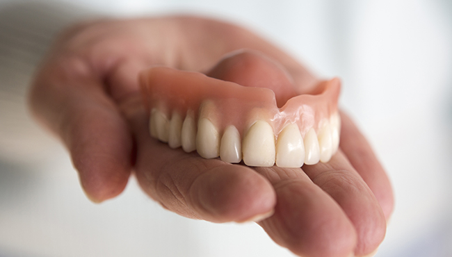 Hand holding a full denture restoration