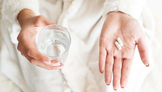 Patient holding antibiotic periodontal therapy pills and glass of water