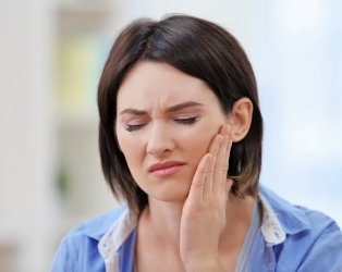 Woman in need of emergency dentistry holding cheek