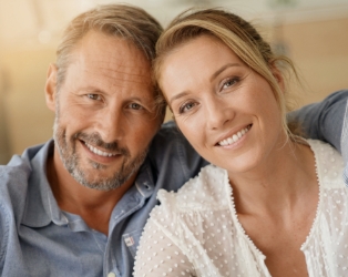 Man and woman smiling after replacing missing teeth