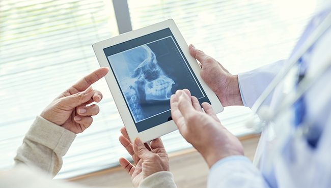 Dentist analyzing diagnostic images of jaw and skull bone