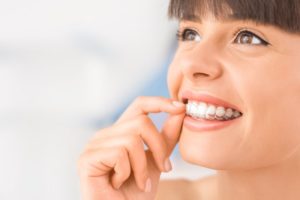 woman smiling inserting Invisalign in Fort Worth