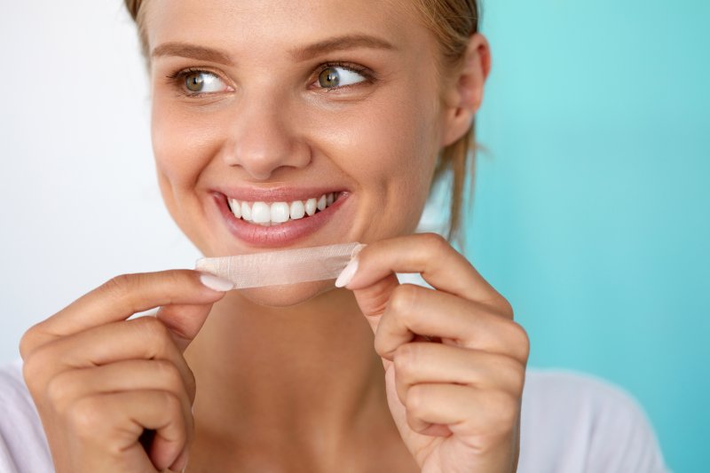 young woman using teeth whitening strip
